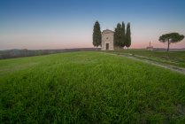 Paisagem pacífica de pequena capela com ciprestes em campo verde vazio remoto ao pôr do sol na Toscana, Itália — Fotografia de Stock