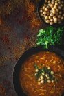 Soupe traditionnelle Harira pour Ramadan dans un bol noir sur fond sombre avec des ingrédients — Photo de stock