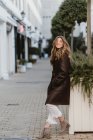 Stylish young woman in vintage leather coat posing on city street — Stock Photo
