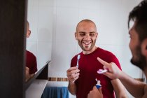 Brincalhão gay casal escovação dentes e brincando em torno de no banheiro — Fotografia de Stock