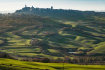 Живописный пейзаж зеленых нагорьев с городом в долине, Тоскана, Италия — стоковое фото