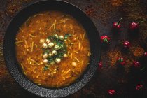 Traditional Harira soup for Ramadan in black bowl on dark background with red peppers — Stock Photo