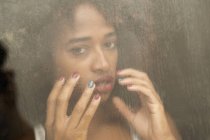 Portrait of sensual black woman behind wet window — Stock Photo
