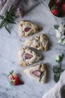 Conjunto de deliciosos scones de morango colocados em mesa de mármore branco perto de flores — Fotografia de Stock