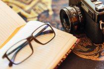 Closeup of open notebook next to a vintage camera on decorative table — Stock Photo