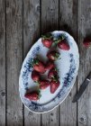 Placa de deliciosas fresas maduras sobre mesa de madera cerca de cuchillo de metal - foto de stock