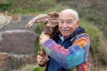 Alter Mann in Jacke bricht an Küste stehendes Steinstück — Stockfoto