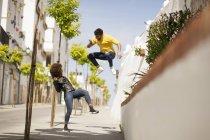 Stylischer junger Kerl springt auf und fotografiert lustige Frauen auf der Straße — Stockfoto