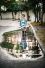 Piccola ragazza che gioca con pozzanghera in strada — Foto stock