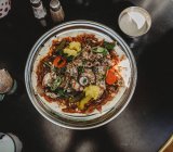 Арабское блюдо с мясом и овощами в миске на черном столе — стоковое фото