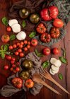 Tomates fraîches et fromage mozzarella avec feuilles de basilic pour salade sur la surface en bois et serviette en tissu — Photo de stock