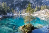 Landschaft des ruhigen azurblauen Sees mit schneebedecktem Ufer und Resort-Gebäude in den Bergen der Schweiz — Stockfoto