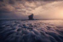 Malerischer Blick auf die Klippe am ruhigen glatten Meeresufer vor grauem Himmel — Stockfoto