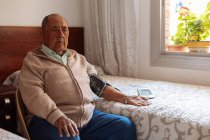 Uomo anziano controllando la pressione arteriosa con la macchina — Foto stock