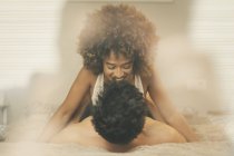 Jeune homme et femme sensuels couchés sur le lit et câlins dans une chambre confortable à la maison — Photo de stock