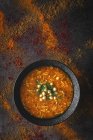 Traditionelle Harira-Suppe für Ramadan in schwarzer Schüssel auf dunkler Oberfläche mit verstreuten Gewürzen — Stockfoto