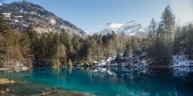 Paisagem de lago azul pacífico com praia nevada e resort de construção em montanhas da Suíça — Fotografia de Stock