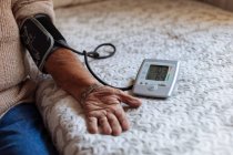 Homem mais velho verificando sua pressão arterial com máquina — Fotografia de Stock