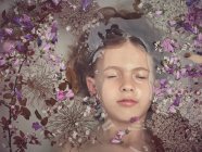 Du dessus de la face de l'enfant dans un liquide entre les pétales frais de fleurs — Photo de stock
