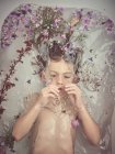 Von oben Kindergesicht in Flüssigkeit zwischen frischen Blütenblättern — Stockfoto