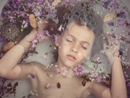 Dall'alto faccia di bambino in liquido tra petali freschi di fioriture — Foto stock