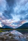 Malerischer Blick auf Wasseroberfläche und Ufer mit Steinhügeln und bewölktem Himmel in Banff, Kanada — Stockfoto