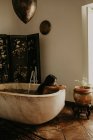 Vista lateral de una mujer bonita tomando un baño en una casa rústica - foto de stock