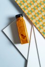 Манго и бутылка смузи из-под тыквы поверх геометрической текстуры в стиле ретро — стоковое фото