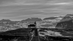 Церковна будівля, розташована біля чорнової сільської дороги проти хмарного неба в Ісландії — стокове фото