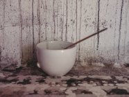 Разбитая керамическая чашка с тонкой кистью возле громоздкой стены в мастерской художника — стоковое фото
