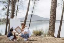 Mãe e menino pintura perto do lago — Fotografia de Stock