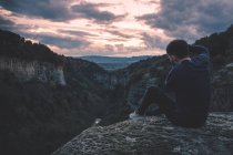 Man with photo camera sitting on hill mountain with magnificent sunset — Stock Photo