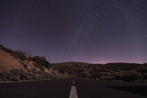 Malerischer Blick auf die Fahrbahn in der spanischen Wüste vor atemberaubendem dunklen Himmel mit leuchtenden Sternen — Stockfoto