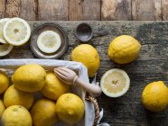 Свежие лимоны и деревянный сжиматель на деревянной доске — стоковое фото