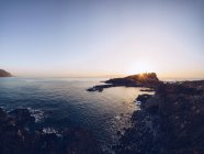 Pittoresco paesaggio di tramonto luminoso sopra tranquilla spiaggia rocciosa con onde increspate, Spagna — Foto stock