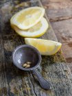 Primo piano di fette di limone e metallo vecchio colino su tavola di legno — Foto stock