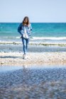Mujer joven caminando en la orilla del mar - foto de stock