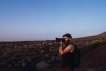 Вид збоку мандрівного чоловіка з рюкзаком беручи фото пейзаж в Душки пустелі, Іспанія — стокове фото