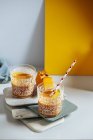 Mango and pumpkin smoothie glasses on stacked boards — Stock Photo