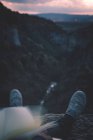 Вид на маленькую реку в каньоне и ноги человека с книгой, сидящего на краю — стоковое фото