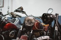 Shabby vintage motorbikes with broken headlights parked inside repair workshop — Stock Photo