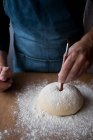 Unbekannter männlicher Koch formt frischen Teig mit Mehl, während er Rosca de Reyes über Holztisch in der Küche kocht. — Stockfoto