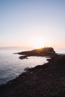 Vista panorámica de la brillante puesta del sol en el cielo despejado iluminando la costa remota vacía, España - foto de stock