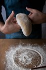 Masculin méconnaissable façonnant la pâte fraîche avec de la farine pendant la cuisson Rosca de Reyes sur une table en bois dans la cuisine . — Photo de stock