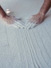 Mani di anonimo artista maschio diffusione grezzo intonaco bianco su superficie piana in officina — Foto stock