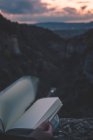 Вид на невелику річку в каньйоні і ноги людини з книгою, що сидить на краю — стокове фото