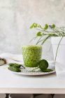 Gesunder grüner Smoothie aus Spinat, Avocado und Kiwi, Apfel und Zitrone im Glas auf Teller — Stockfoto
