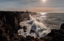 Штормових хвиль на західному узбережжі Ісландії і Svrtuloft маяк на заході сонця — стокове фото