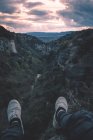 Vista a piccolo fiume in canyon e gambe di persona seduta sul bordo — Foto stock