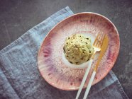 Faca e garfo com alcachofra fresca inteira em placa de cerâmica rosa — Fotografia de Stock